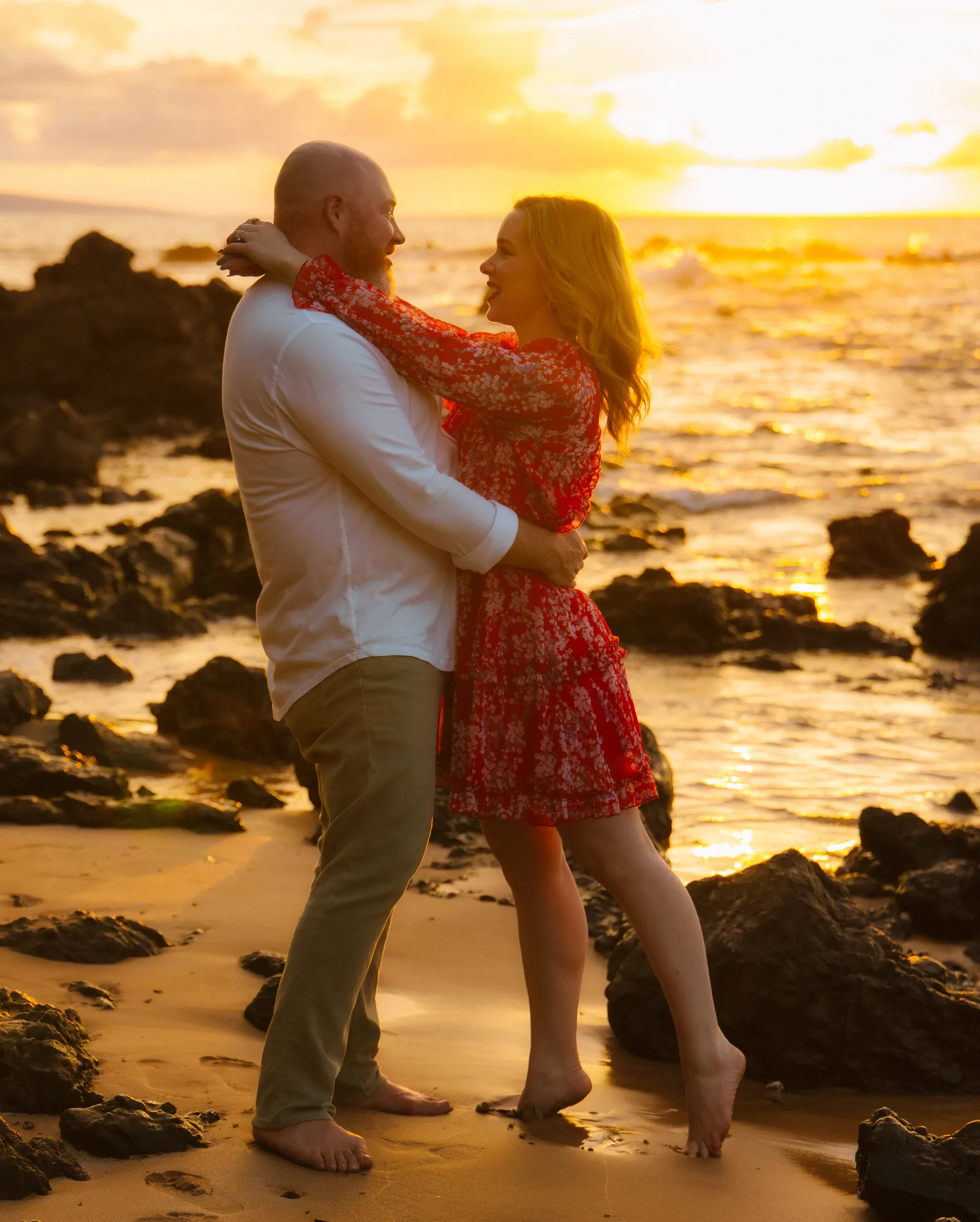 A couple embracing among lava rocks in heavy golden-hour light