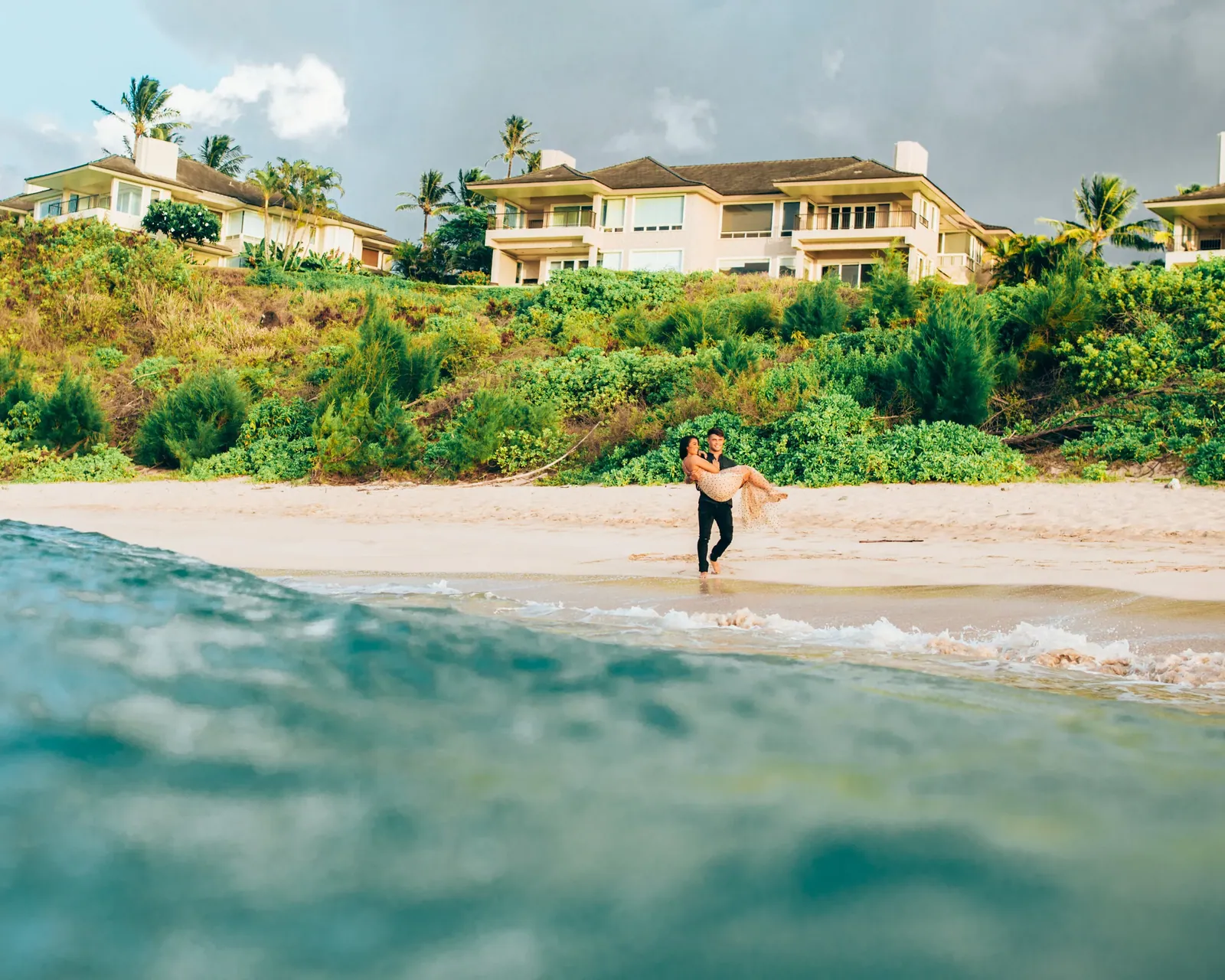 Wide shot of a couple standing in shallow turquoise water on a Maui beach
