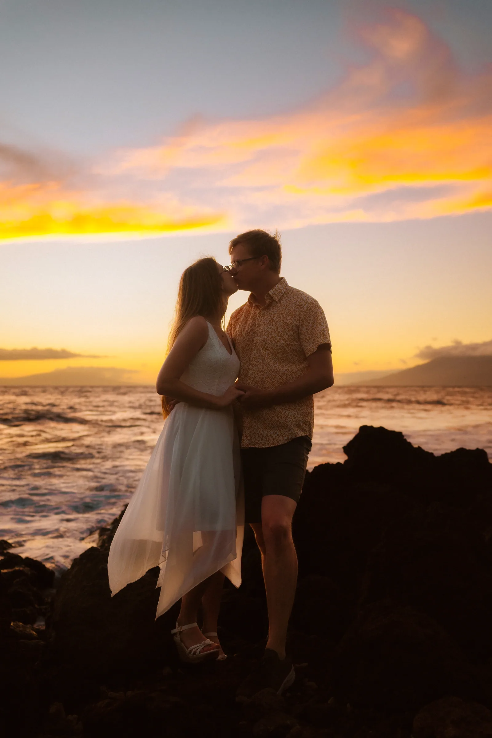 A couple kissing in silhouette against a vivid sunset