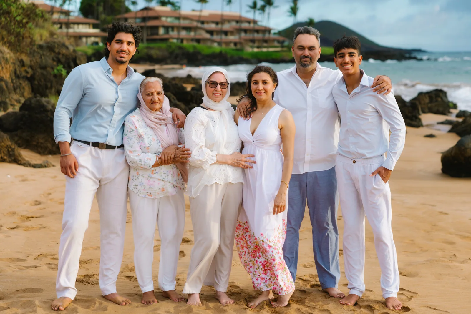 A multi-generation family in white linen photographed on the sand