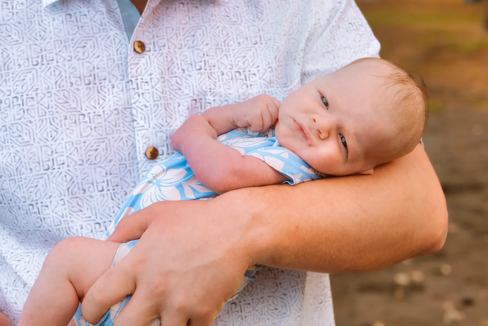A newborn asleep in a parent's arms, photographed close