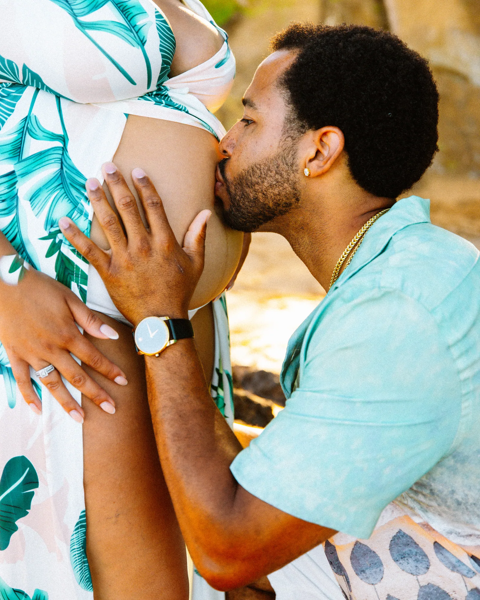 A partner kissing the bump with both their hands resting on it