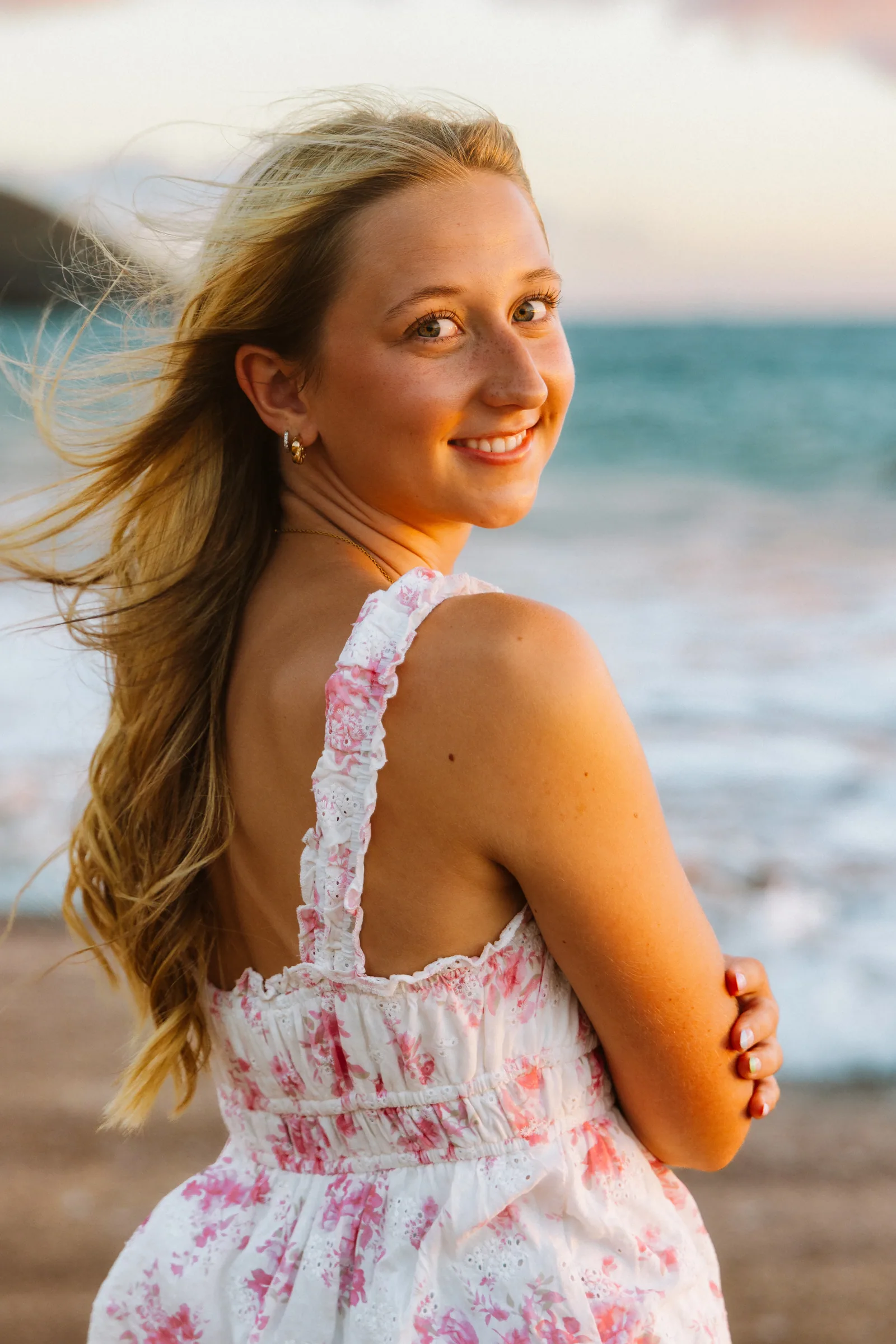 A senior portrait with the wind through her hair and the surf behind